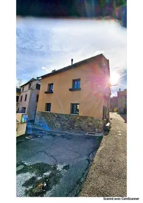 a building with the sun shining on the side of it at Maison QUÉRIGUT in Quérigut