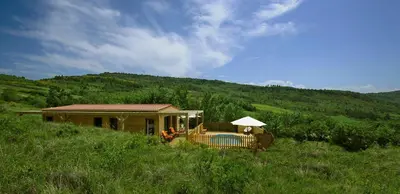 a house in a grassy hill with a porch at Maison - piscine - Vue vignobles coeur de nature in Roquetaillade