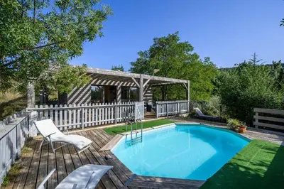 a swimming pool on a wooden deck with a white fence at Maison - piscine - Vue vignobles coeur de nature in Roquetaillade