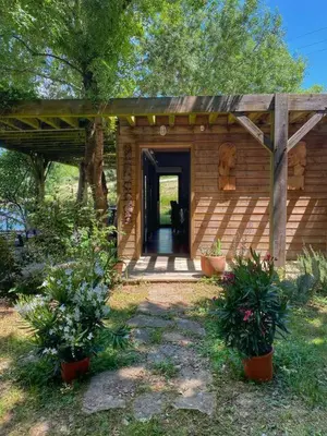 a small wooden house with a black cat in the doorway at Maison - piscine - Vue vignobles coeur de nature in Roquetaillade