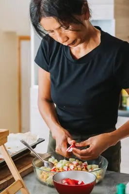 a woman standing in a kitchen preparing food at Lodge milieu - Piscine privée Terrasse - in Roquetaillade