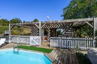 a wooden pergola next to a swimming pool at Lodge milieu - Piscine privée Terrasse - in Roquetaillade