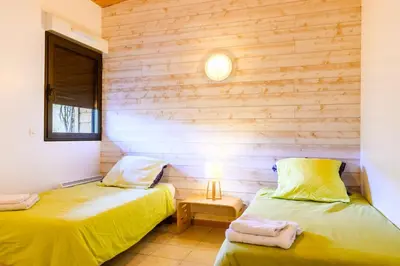 two beds in a room with wooden walls at Lodge milieu - Piscine privée Terrasse - in Roquetaillade