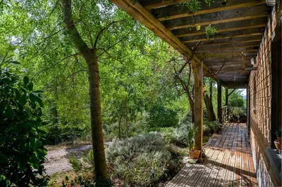 a porch of a house with a wooden walkway at Ecolodge - Calme - Piscine privée - vue nature in Roquetaillade