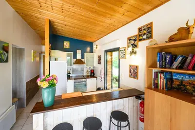 a kitchen with a counter with chairs and a vase of flowers at Ecolodge - Calme - Piscine privée - vue nature in Roquetaillade