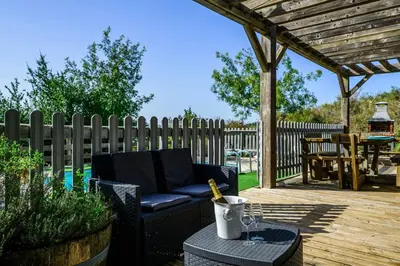 a patio with a black couch and a wooden fence at Ecolodge - Calme - Piscine privée - vue nature in Roquetaillade