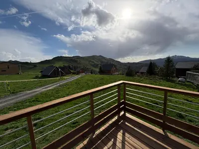a wooden balcony with a view of a field and mountains at Chalet Echo des Montagnes in Camurac