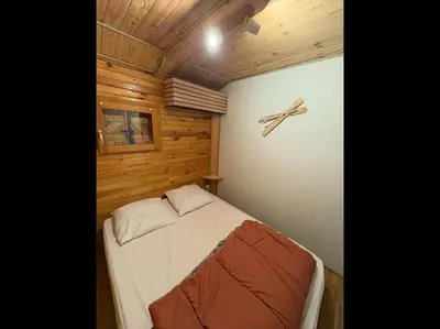 a small bed in a room with wooden walls at Chalet Echo des Montagnes in Camurac