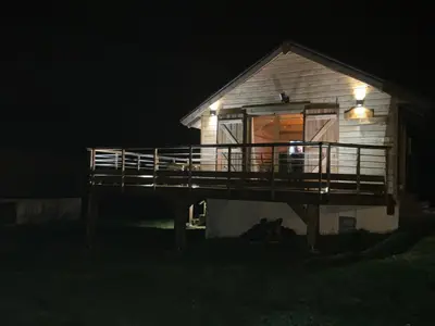 a small house with a deck at night at Chalet Echo des Montagnes in Camurac