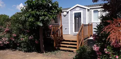 a small white house with a wooden deck at omer port la nouvelle in Port-la-Nouvelle