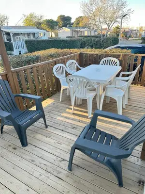 a table and chairs on a wooden deck at MOBIL HOME Le Soleil,3CH,6PERS in Port-la-Nouvelle
