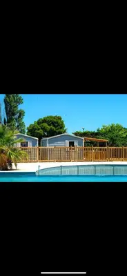 a house with a deck and a swimming pool at MOBIL HOME Le Soleil,3CH,6PERS in Port-la-Nouvelle