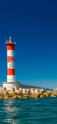 a red and white lighthouse on a pier with water at MOBIL HOME Le Soleil,3CH,6PERS in Port-la-Nouvelle