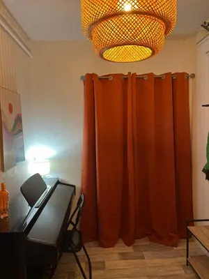 a room with an orange curtain and a lamp at Maison de Village in Lacrouzette