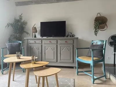 a living room with chairs and a tv on a cabinet at Maison de Village in Lacrouzette