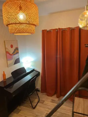 a living room with orange curtains and a piano at Maison de Village in Lacrouzette