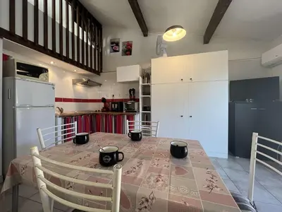 a kitchen with a table with chairs and a refrigerator at Pavillon confort avec parking et piscine collective - GN180-057 in Gruissan