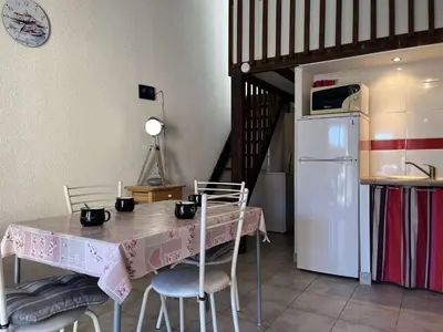 a kitchen with a table with chairs and a refrigerator at Pavillon confort avec parking et piscine collective - GN180-057 in Gruissan