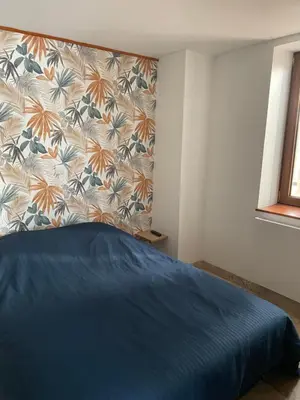 a bedroom with a blue bed with a floral headboard at studio cosy a la ferme in Saint-Julia
