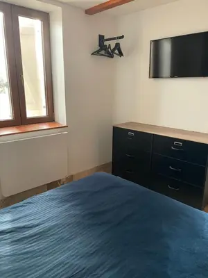 a bedroom with a bed and a flat screen tv at studio cosy a la ferme in Saint-Julia