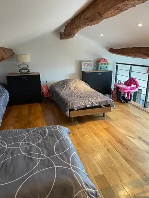 a bedroom with two beds and a wooden floor at studio cosy a la ferme in Saint-Julia
