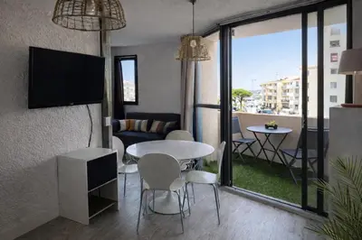 a living room with a table and chairs and a tv at L'Escapade Marine in Gruissan
