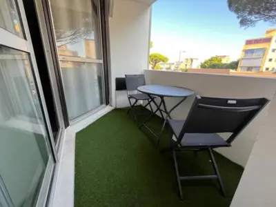 a balcony with two chairs and a table with green grass at L'Escapade Marine in Gruissan