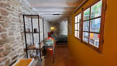 a hallway with a stone wall and a table and window at La Concha 1 in Conques-sur-Orbiel
