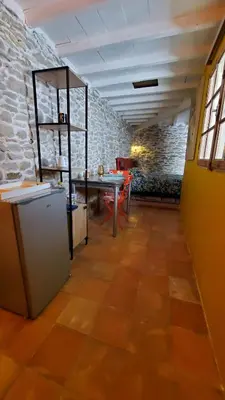 a room with a table and a table and a stone wall at La Concha 1 in Conques-sur-Orbiel