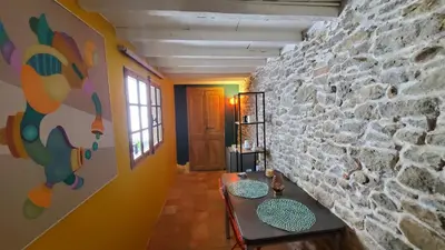 a living room with a stone wall and a table at La Concha 1 in Conques-sur-Orbiel
