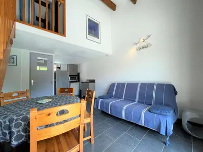 a bedroom with a blue bed and a kitchen at Maison front de plage avec terrasse Grazel - GN210-027 in Gruissan