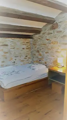 a small bedroom with a bed and a desk at la source et la sorciere in Pradelles-Cabardès