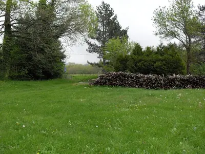 a pile of logs in a field of grass at la source et la sorciere in Pradelles-Cabardès