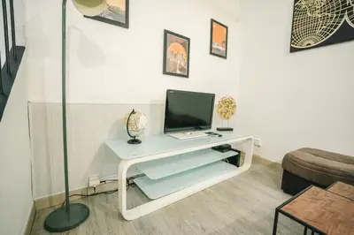 a living room with a tv on a white table at Au pied des remparts- Maison de caractère-3 Ch-AC in Carcassonne