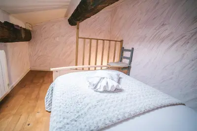 a bedroom with a white bed and a chair at Au pied des remparts- Maison de caractère-3 Ch-AC in Carcassonne