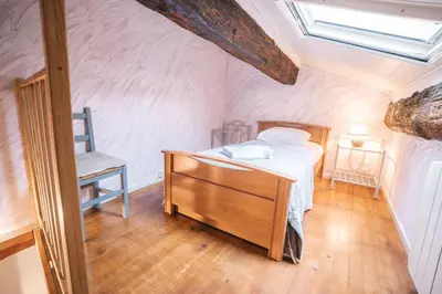 a bedroom with a bed and a chair in a attic at Au pied des remparts- Maison de caractère-3 Ch-AC in Carcassonne