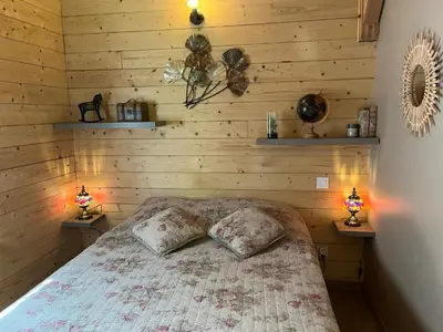 a bedroom with a bed with wooden walls and two lamps at Le Chalet in Fanjeaux