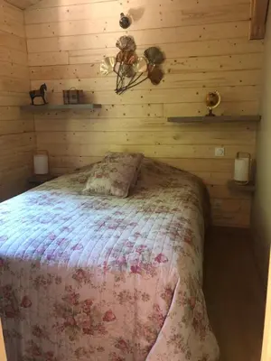 a bedroom with a bed in a wooden wall at Le Chalet in Fanjeaux