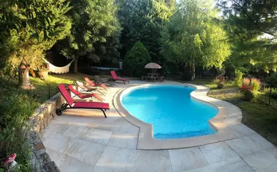 a swimming pool with two chairs and a table at Le Chalet in Fanjeaux