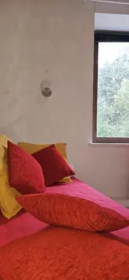a bed with red and yellow pillows and a window at Domaine de Gondal, demeure de charme in Palaja