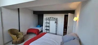a bedroom with two beds and a chair and a mirror at Domaine de Gondal, demeure de charme in Palaja