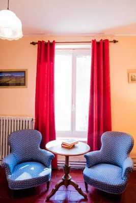 two chairs and a table in a room with red curtains at Domaine de Gondal, demeure de charme in Palaja