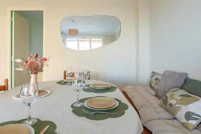 a table with plates and glasses and a couch at Les Jacinthes - Spacious sea view in Port-la-Nouvelle