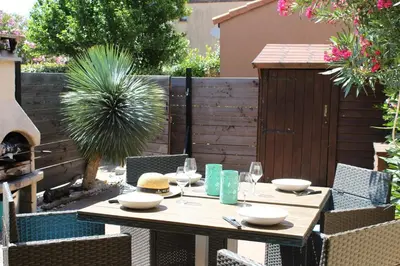 a wooden table with plates and glasses on a patio at Maison 2 pièces mezzanine - Gruissan GN020-071 in Gruissan