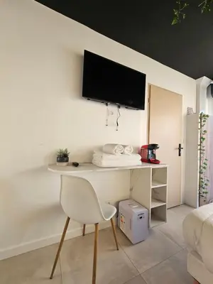 a white desk with a chair and a tv on a wall at Evasion balneo in Narbonne