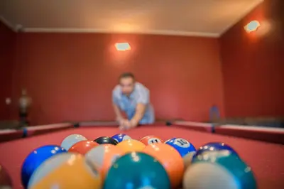 a man is standing behind a pool table at Le Château de La Seigne près de Carcassonne in Villemoustaussou