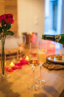 a bottle of wine being poured into two wine glasses at La Villa Lova - Loveroom avec spa privatif à Pamiers in Pamiers
