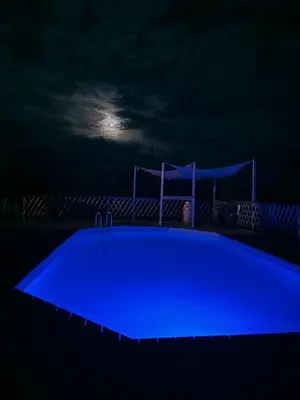 a blue pool at night with the moon in the background at Oyana in Montgradail
