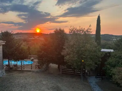 a sunset over a pool with a fence and trees at Oyana in Montgradail