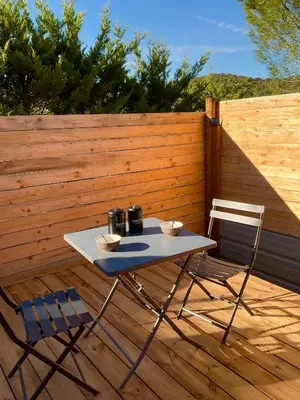 a table and two chairs on a wooden deck at A l ombre des pods Chardonnay et spa in Saint-Hilaire